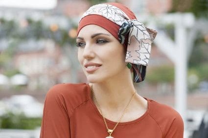Woman with no hair wearing a bamboo hat with scarf.