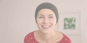 A lady who has lost her hair due tto cancer or alopecia and is wearing a beanie hat she purchased from Roches