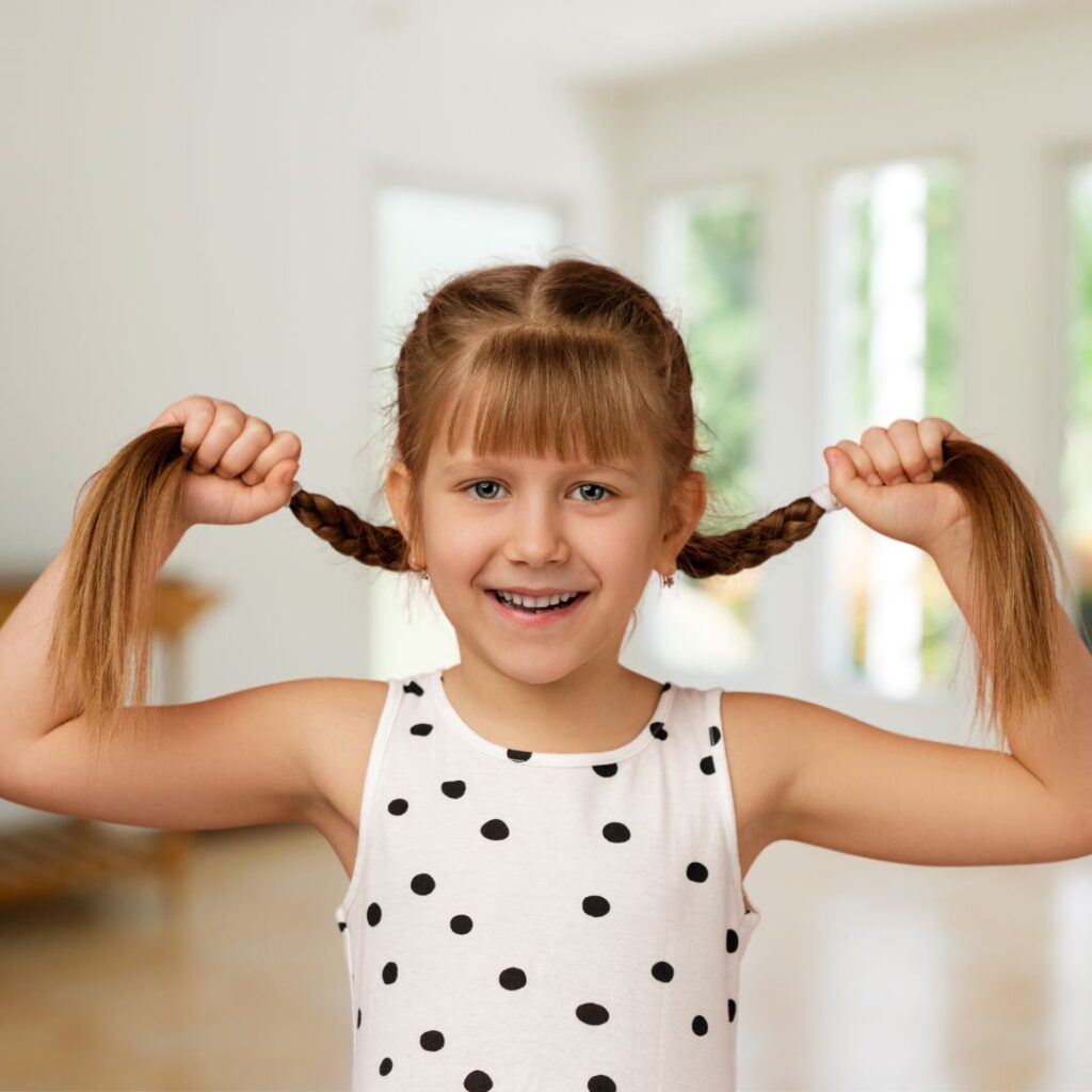 A little girl posting with her hair in pigtails